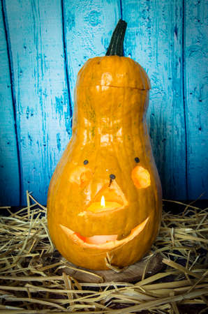 cute artificial halloween orange pumpkin decoration made from paper and glass with burning candle insideの写真素材
