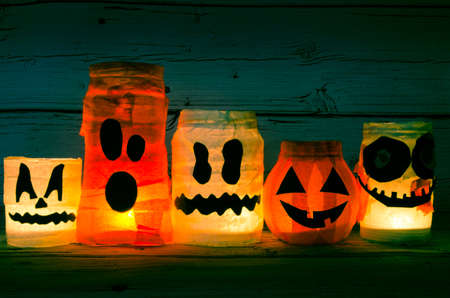 cute artificial halloween orange pumpkin decoration made from paper and glass with burning candle insideの写真素材