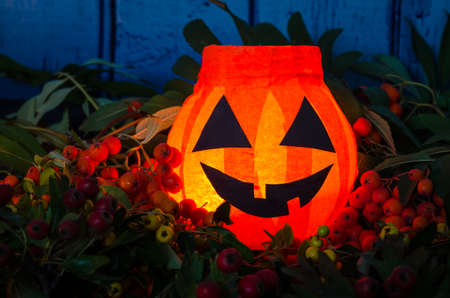 cute artificial halloween orange pumpkin decoration made from paper and glass with burning candle insideの写真素材