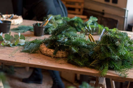 burning candles, scissors and green twigs components on wooden tableの写真素材