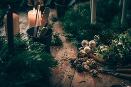 burning candles, scissors and green twigs components on wooden tableの写真素材