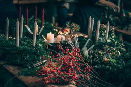 burning candles, scissors and green twigs components on wooden tableの写真素材