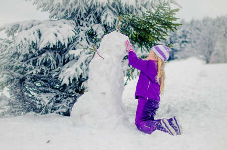 adorable girl in winter forest enjoying snowy atmosphereの写真素材