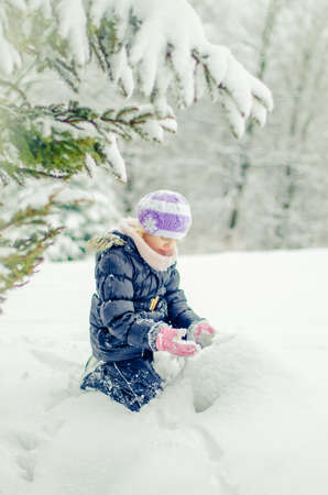 adorable girl in winter forest enjoying snowy atmosphereの写真素材