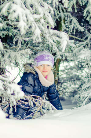adorable girl in winter forest enjoying snowy atmosphereの写真素材