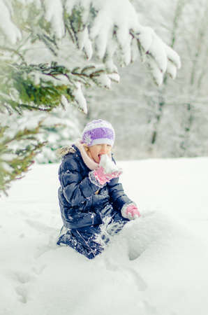 adorable girl in winter forest enjoying snowy atmosphereの写真素材