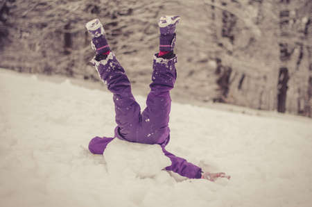 adorable girl having fun in sleigh in winter countryside up side down going crazyの写真素材