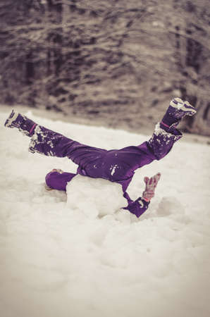 adorable girl having fun in sleigh in winter countryside up side down going crazyの写真素材