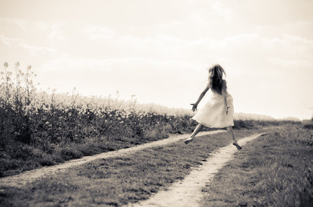 adorable blond child in rural path having fun with white lace umbrellaの写真素材