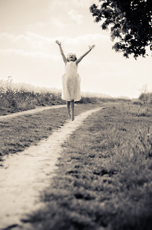 adorable blond child in rural path having fun with white lace umbrellaの写真素材