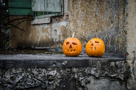 two orange carved halloween pumpkins in front of the houseの写真素材