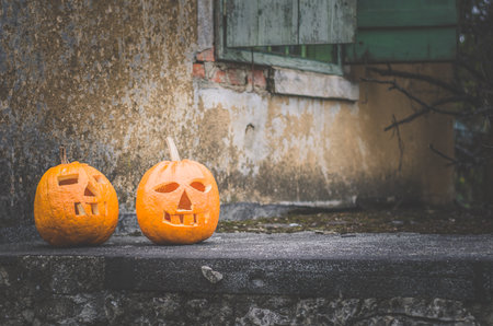 two orange carved halloween pumpkins in front of the houseの写真素材