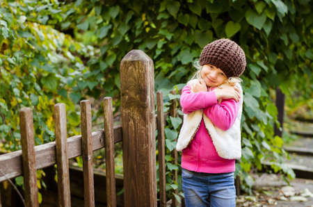 portrait of happy smiling girl with long blond hair in colorful autumnal atmosphere posing in green park full of fallen leavesの写真素材