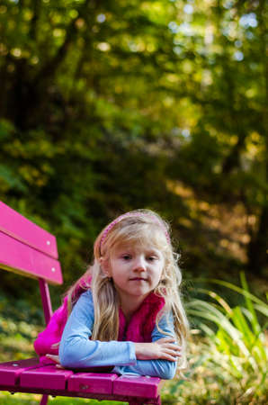 portrait of happy smiling girl with long blond hair in colorful autumnal atmosphere posing in green park full of fallen leavesの写真素材