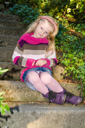 portrait of happy smiling girl with long blond hair in colorful autumnal atmosphere posing in green park full of fallen leavesの写真素材