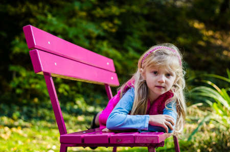 portrait of happy smiling girl with long blond hair in colorful autumnal atmosphere posing in green park full of fallen leavesの写真素材