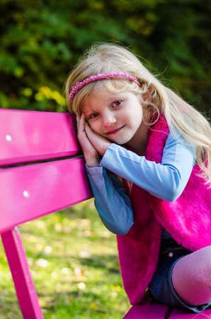 portrait of happy smiling girl with long blond hair in colorful autumnal atmosphere posing in green park full of fallen leavesの写真素材