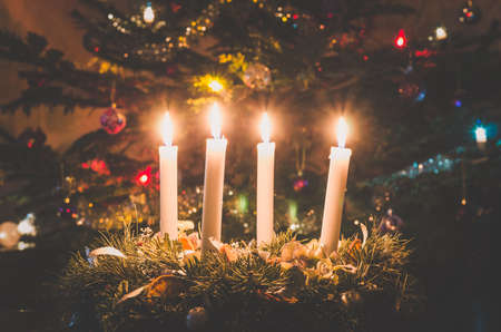 one burning candle concept with shining bokeh glittering ligts on christmas tree on dark backgroundの写真素材