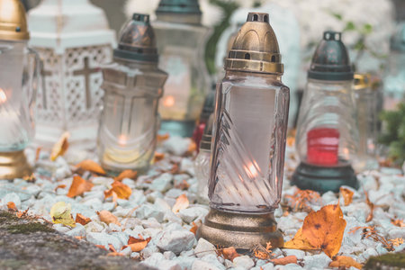 burning candle and chrysanthemum flower decoration on grave in the cemetery