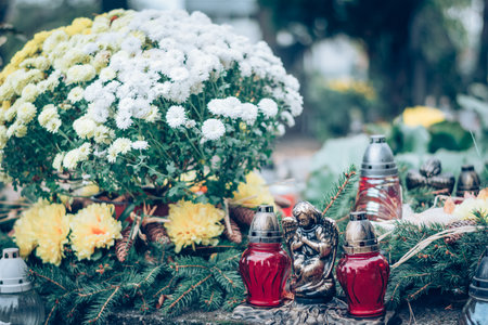burning candle and chrysanthemum flower decoration on grave in the cemetery