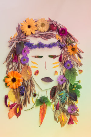 romantic woman face with natural hair made from colorful leaves and bright flowers on white backgroundの写真素材