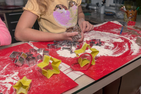 lovely child girl tasting and enjoying sweet color paste while cooking gingerbread cookies for...