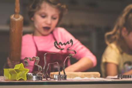 lovely child girl tasting and enjoying sweet color paste while cooking gingerbread cookies for christmas tableの写真素材