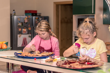 lovely child girl tasting and enjoying sweet color paste while cooking gingerbread cookies for christmas tableの写真素材