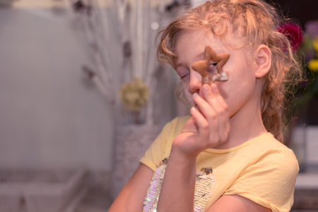 lovely child girl tasting and enjoying sweet color paste while cooking gingerbread cookies for christmas tableの写真素材