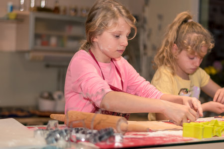 lovely child girl tasting and enjoying sweet color paste while cooking gingerbread cookies for christmas tableの写真素材