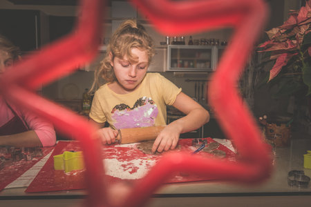 lovely child girl tasting and enjoying sweet color paste while cooking gingerbread cookies for christmas tableの写真素材