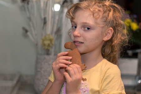 lovely child girl tasting and enjoying sweet color paste while cooking gingerbread cookies for christmas tableの写真素材
