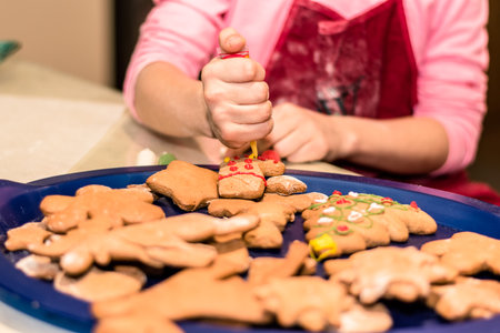 lovely child girl tasting and enjoying sweet color paste while cooking gingerbread cookies for christmas tableの写真素材
