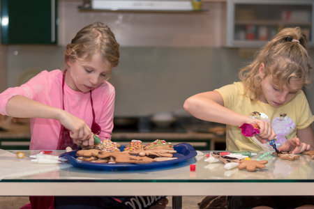 lovely child girl tasting and enjoying sweet color paste while cooking gingerbread cookies for christmas tableの写真素材
