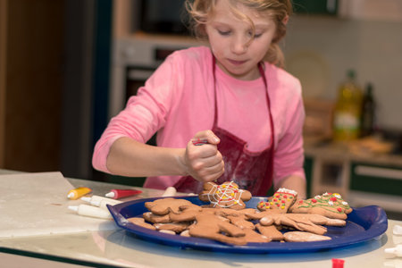 lovely child girl tasting and enjoying sweet color paste while cooking gingerbread cookies for christmas tableの写真素材