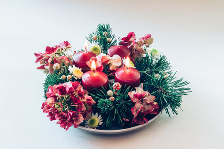 4 red advent candles in religious cristian traditional wreath decorated with green fir and hortensia flowersの写真素材