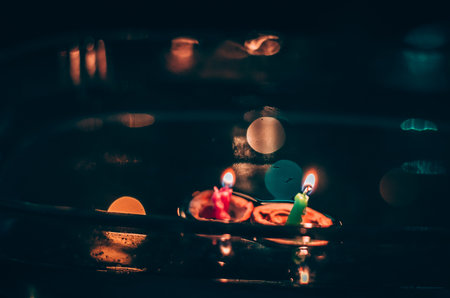 nutshell with burning candles floating on water surface in dark, European christmas traditionの写真素材