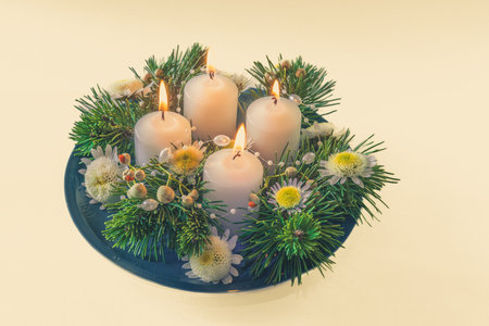 4 white advent candles in religious cristian traditional wreath decorated with green fir and flowersの写真素材