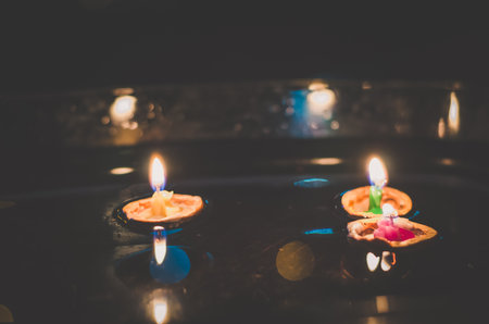 nutshell with burning candles floating on water surface in dark, European christmas traditionの写真素材
