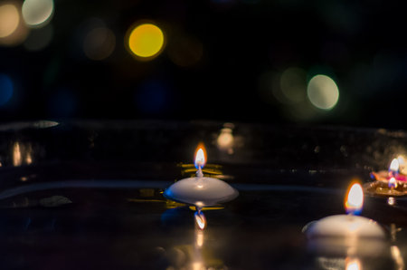 nutshell with burning candles floating on water surface in dark, European christmas traditionの写真素材