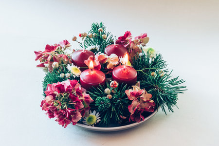 4 red advent candles in religious cristian traditional wreath decorated with green fir and hortensia flowersの写真素材