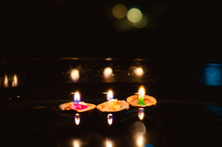 nutshell with burning candles floating on water surface in dark, European christmas traditionの写真素材
