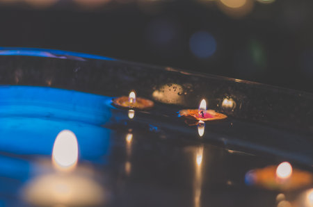 nutshell with burning candles floating on water surface in dark, European christmas traditionの写真素材