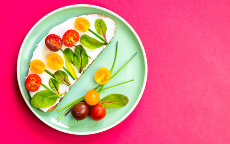 bread with butter, red and orange cherry tomatoes designed as flowers with green chives and basil herbsの写真素材