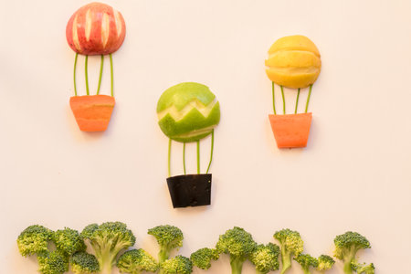 flying balloon made from apples,broccoli and carrots, isolated colorful food ideasの写真素材