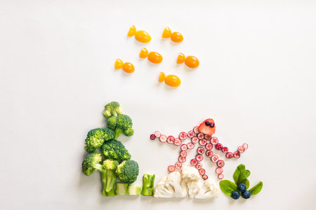 octopus made from red fruits, fish from orange tomato with sea world from cauliflower, broccoli and green herbs isolated on white backgroundの写真素材