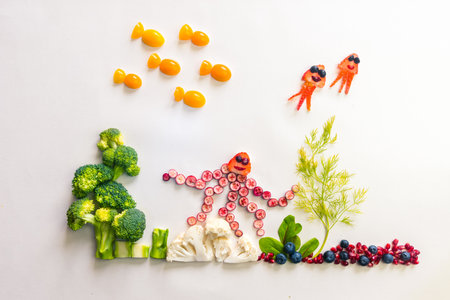 octopus made from red fruits, fish from orange tomato with sea world from cauliflower, broccoli and green herbs isolated on white backgroundの写真素材