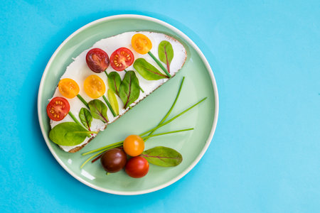 bread with butter, red and orange cherry tomatoes designed as flowers with green chives and basil herbsの写真素材