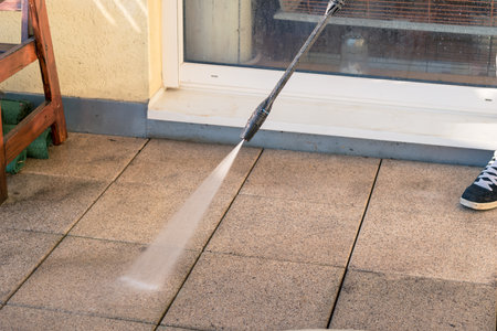 man with tube cleaning terrace with water pressure from dirtの写真素材