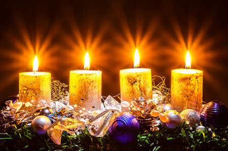 four burning advent candles with decoration and adornments on black background copy spaceの写真素材
